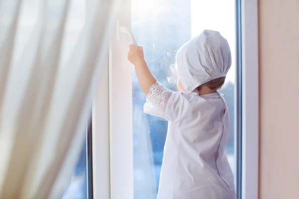 küçük bir kız pencereden dışarı bakarak bir pencere üzerinde ayakta