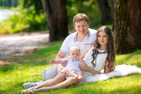 Vacker familj med en baby i parken — Stockfoto