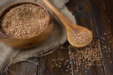 Karabuğday kabuğu çıkarılmış tane kase ve grunge arka plan üzerinde buğday ile ahşap Kepçe