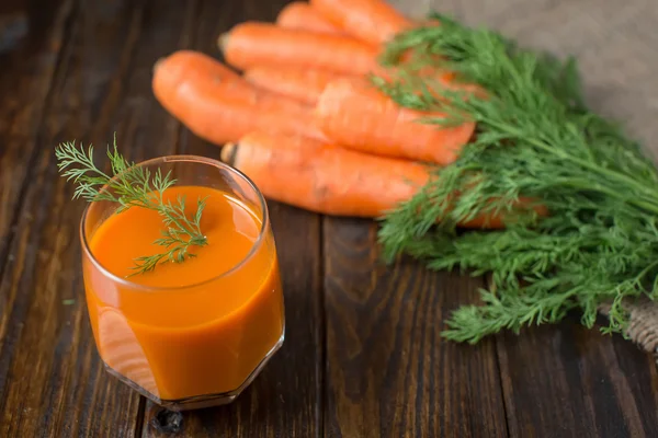 Carrot juice and fresh carrot on a wooden background — Stock Photo, Image