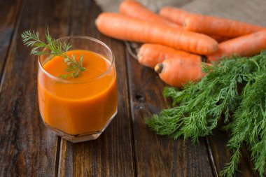 Havuç suyu ve ahşap arka plan üzerinde taze havuç
