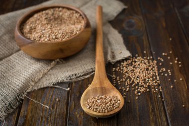 Karabuğday kabuğu çıkarılmış tane kase ve grunge arka plan üzerinde buğday ile ahşap Kepçe