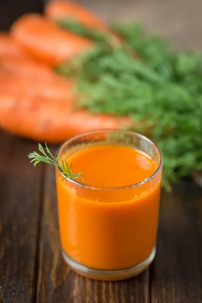 Havuç suyu ve ahşap arka plan üzerinde taze havuç