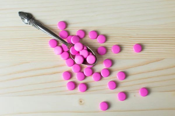 Pharmacy background. Full spoon of pills on a wooden table. Medicine. Natural background. Capsule on a spoon. Close up — Stock Photo, Image