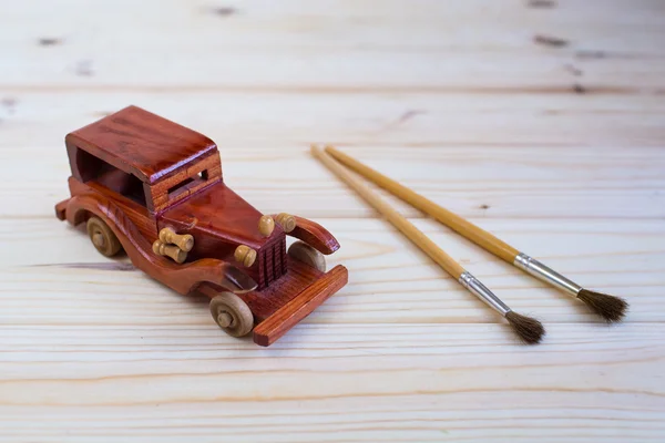 Wooden toy car and a brush to paint on the wooden background