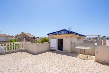 Geniş çatı alanı desenli fayanslar, açık kamara, mavi çatı ve mahalle manzaralı.