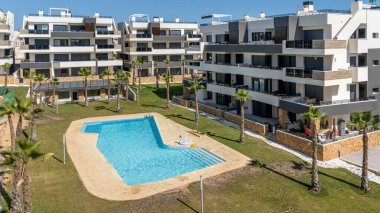 Açıklama (maksimum 20 kelime): Yüzme havuzları, palmiye bahçeleri, çatı terasları ve güneşli ortamlarda açık hava rahatlama bölgeleri içeren geniş modern kompleks