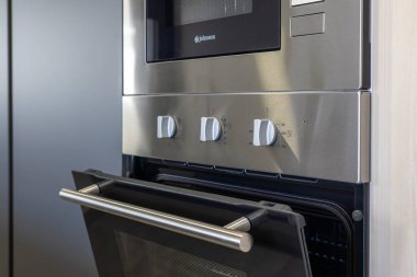 Paslanmaz çelik fırın modern mutfak ünitesinde sıcaklık ve zamanlayıcı düğmeleri gösteriyor.