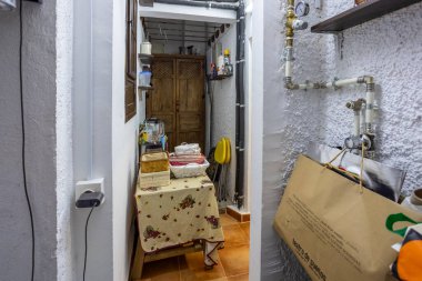 Açığa çıkan borular, ahşap dolap ve ev eşyalarıyla dolu küçük bir depo.