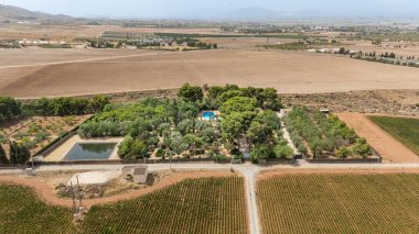 Geniş bir kırsal alanda verimli ağaçlar, havuz ve tarım arazisi olan geniş bir kırsal alan.