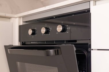 Metal düğmeleri ve mutfak kapısı olan modern bir fırının yakın çekimi..