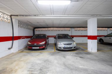 Covered garage with parked cars and painted red stripe on concrete walls