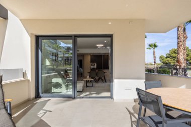 Yuvarlak masalı veranda ve cam kapılardan içeri bakan sandalyeler.