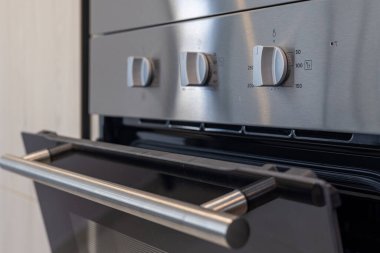 Modern bir mutfak fırınının fırın kapı kolu ve kontrol düğmelerinin detaylı görüntüsü