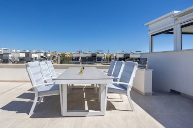 Amanecer apartmanlarının terasında minderli sandalyeli şık bir açık hava yemek masası..