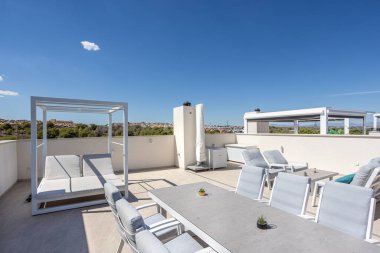 Amanecer kompleksindeki geniş çatı terası, dinlenme yerleri ve yemek masası..