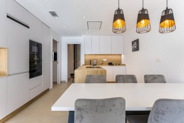 Modern mutfak ve yemek odası. Kolye ışıkları, ahşap ada ve gösterişli dolaplar.