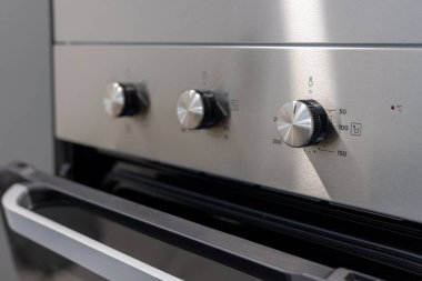 Açık kapılı elektrikli mutfak fırınının detaylı görüntüsü ve üç döner kontrol düğmesi