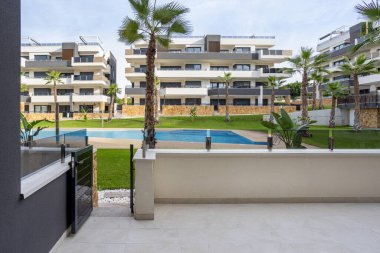 Tropikal bahçeye bakan terası ve ortak havuz girişi olan çağdaş bir daire.