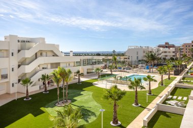 Havuzu, tropikal bitkileri ve manikürlü çimleri olan lüks apartman binalarının manzarası.