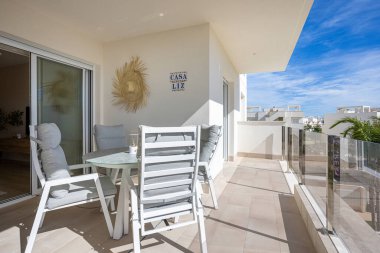 Modern balkon yemek sandalyeleri, cam masa, saman dekoru ve Casa Liz fayans tabelası.