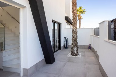 İçinde palmiye ağaçları, sürgülü kapılar ve temiz minimalist duvarlar bulunan küçük çağdaş bir avlu.