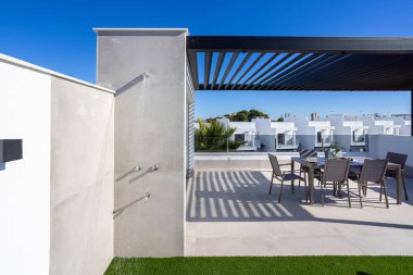 Açık hava duşlu, yemek masalı, pergolu ve güneşli manzaralı bir çatı.