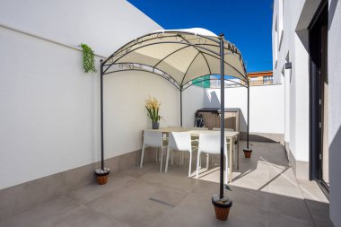 Güneşli özel teras, gölgelik, yemek takımı, saksı bitkileri ve temiz döşeme döşemeleri