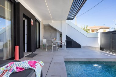 Özel havuzu, şezlongları ve gölgeli açık hava yemek alanının yer aldığı çağdaş bir teras.