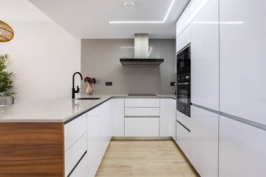 Parlak dolaplar, entegre aletler ve ahşap aksan detaylarıyla modern minimalist mutfak..