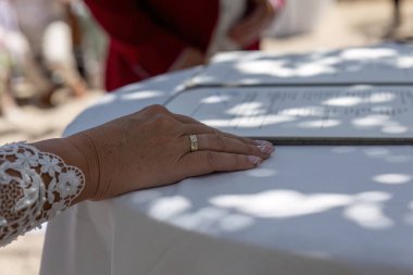 Dantel elbiseli gelinin yakını damatlara yüzük takıyor kırmızı takım elbiseli adam yeminlerini ederken.