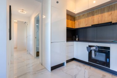 İçinde mermer zemin koridoru, modern mutfak ve banyo girişi olan çağdaş bir daire.