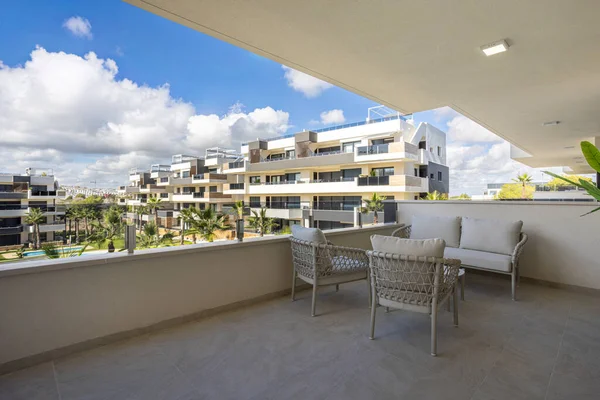 Yastık kaplı balkon alanı ve modern apartman kompleksinin manzarası.