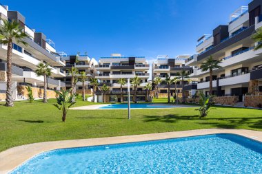 Birden fazla havuz, palmiye ağaçları ve manzaralı yeşil açık alan içeren modern yerleşim yerleri.