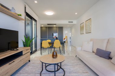Kanepesi, televizyonu, yemek masası, mutfağı ve şık iç dekorasyonu olan çağdaş bir yaşam alanı.