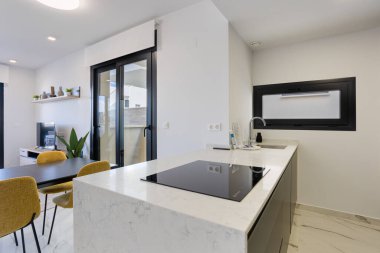 Mermer adalı çağdaş mutfak, siyah indüksiyon aşçı, üst, pencere ve yemek alanı manzaralı.