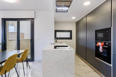 Modern mutfak tasarımı mermer tezgah adası, indüksiyon aşçısı üstü ve parlak siyah dolaplar.