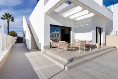 Geniş modern teras. Açık havada oturma, fayanslı zemin ve çatıya çıkan merdivenler var.