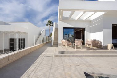 Açık hava sandalyeleri, döşeme döşemeleri ve çatıya çıkan merdivenleri barındıran geniş güneşli teras.