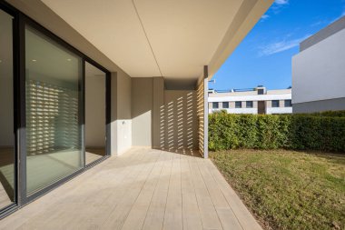 Güneşli zemin terası ahşap görünümlü fayanslar, sürgülü kapılar, mahremiyet duvarı ve bahçe manzaralı.