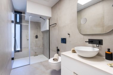 Günümüz banyosunda duş, nötr fayanslar, damar lavabosu ve parlak siyah eşyalar var.