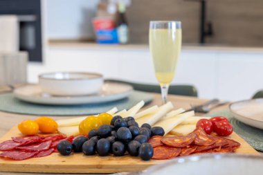 Kahvaltı masası, peynir, zeytin, pişirilmiş et ve şampanya bardağı.