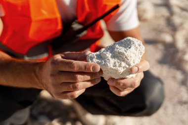 İnşaat mühendisi açık maden sahasındaki kireçtaşı kayalarını inceliyor. Hammadde ve sanayi kavramı