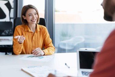 İş kadını bir müşteriyle konuşuyor, verimli bir ofis toplantısında iş görüşmeleri yapıyor ve tartışıyor.