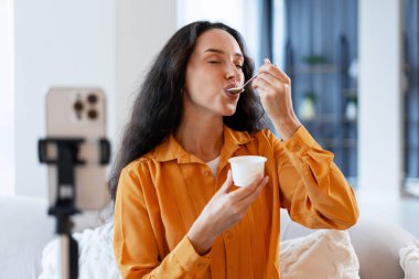 Evde canlı yayında yoğurttan hoşlanan bir kadın sosyal medya takipçileri için içerik yaratıyor. Sağlıklı gıda ve çevrimiçi etki kavramı