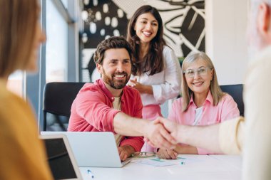 İş adamları anlaşma yapıyor, modern ofis toplantısında el sıkışıyorlar. Takım işbirliği, anlaşma sağlama