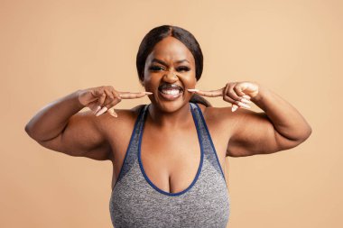 Mutlu siyah, iri yarı kadın parmaklarını gülümseyen ağzına gösteriyor, duygu ve kendine güvenini gösteriyor.