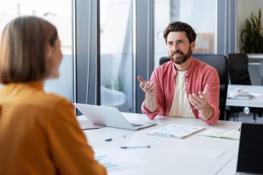 Mutlu, gülümseyen orta yaşlı adam güzel bir kadınla konuşuyor, proje planlıyor, modern ofiste çalışan iki yönetici var. İş konsepti