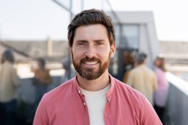 Sıradan kıyafetler giymiş, gülümseyen sakallı adam sokakta poz veren kameraya bakıyor. Kendine güvenen bir iş adamı. Reklam kavramı