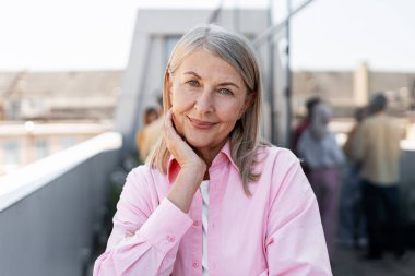 Mutlu, neşeli, olgun kadın şık giyinmiş sokakta poz veren kameraya bakıyor. Reklam kavramı